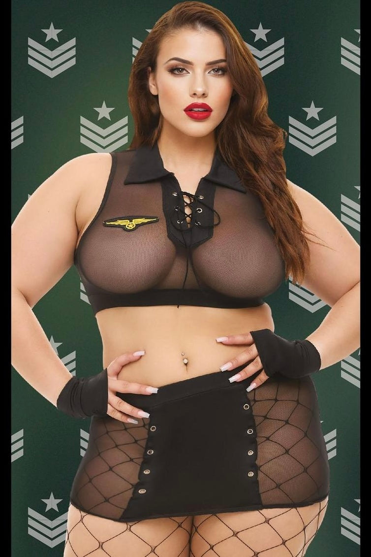 Woman wearing a black outfit with a star emblem on a green background with military insignia.